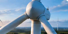 Wind turbine hub and blades over green hills